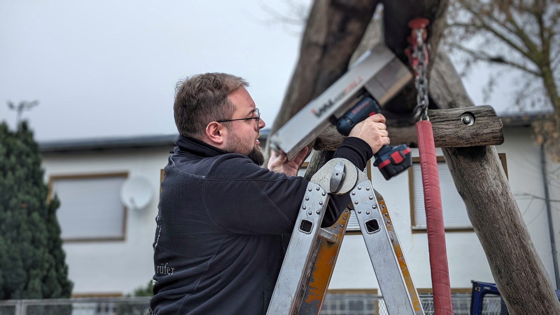 Prüfer untersucht ein Holzbauteil auf einem Spielplatz